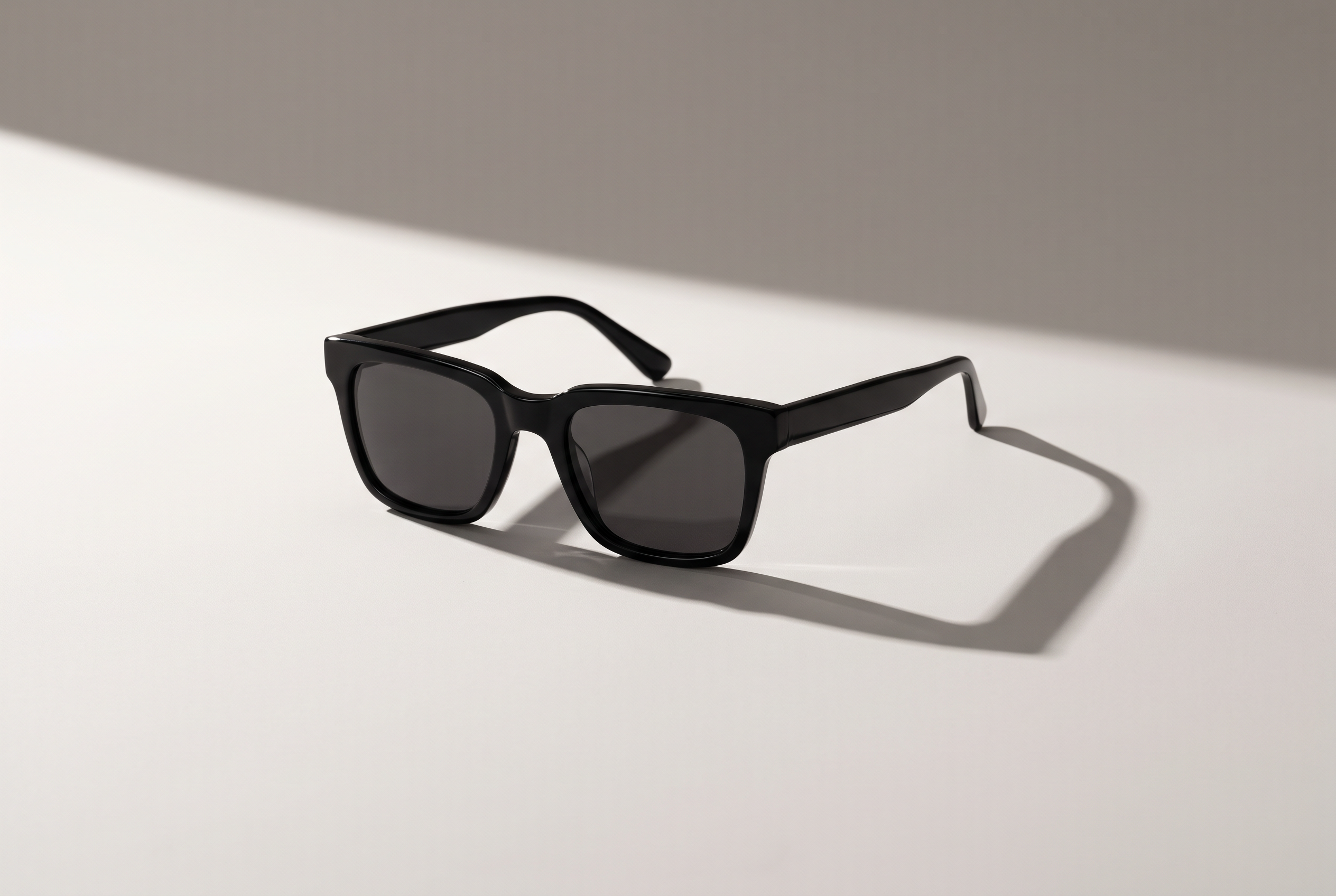 Black square acetate Welham sunglasses casting a long diagonal shadow